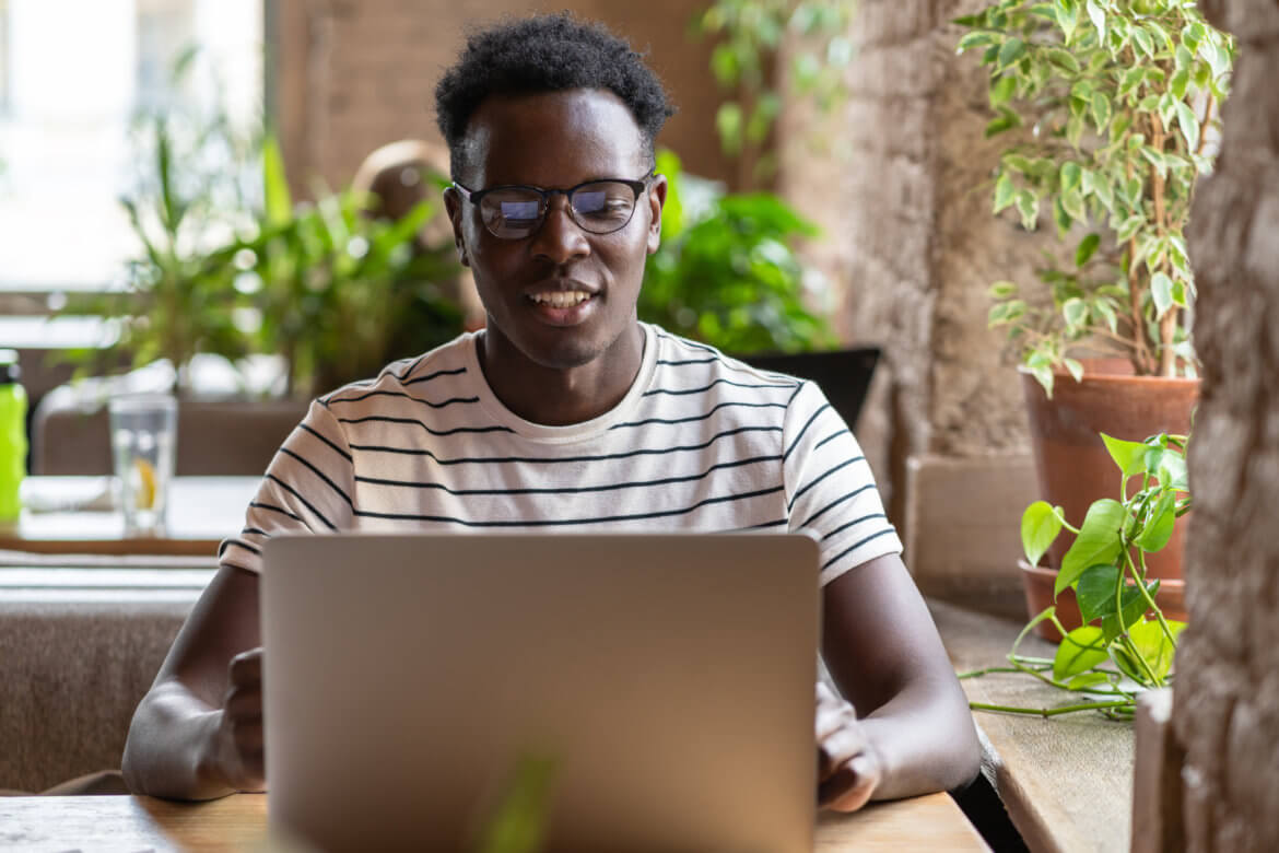 A student learns about AI and audit technology remotely while working from a well-lit cafe.