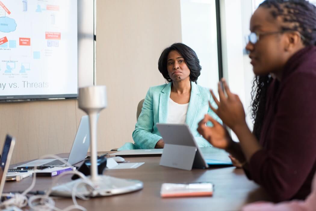 Two people sit at a conference table discussing a presentation on risk management, threats, and more.